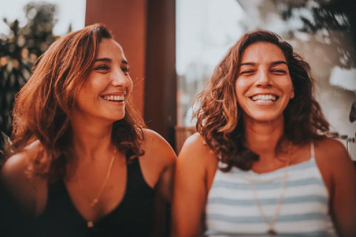 Two happy women sharing a laugh in an outdoor setting, exuding joy and friendship.