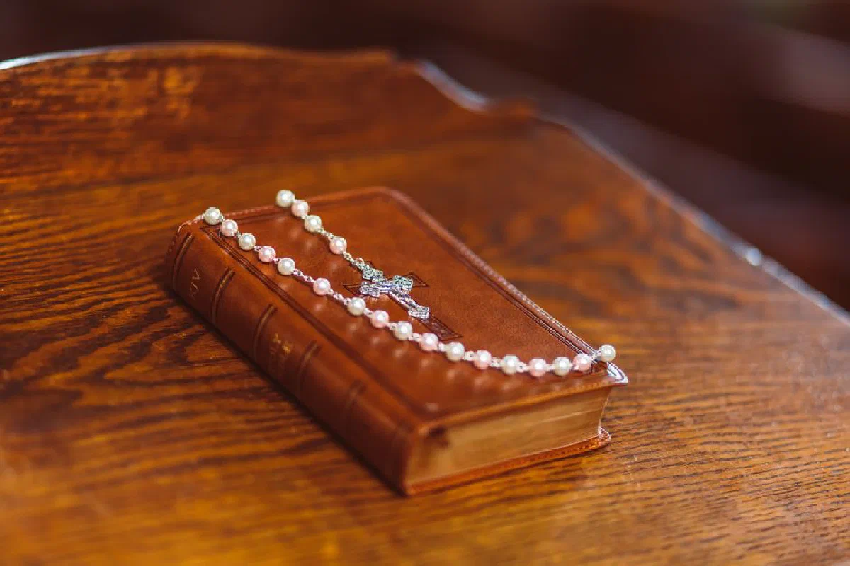 A close-up shot of a Bible and rosary beads on a polished wooden surface, highlighting faith and spirituality.