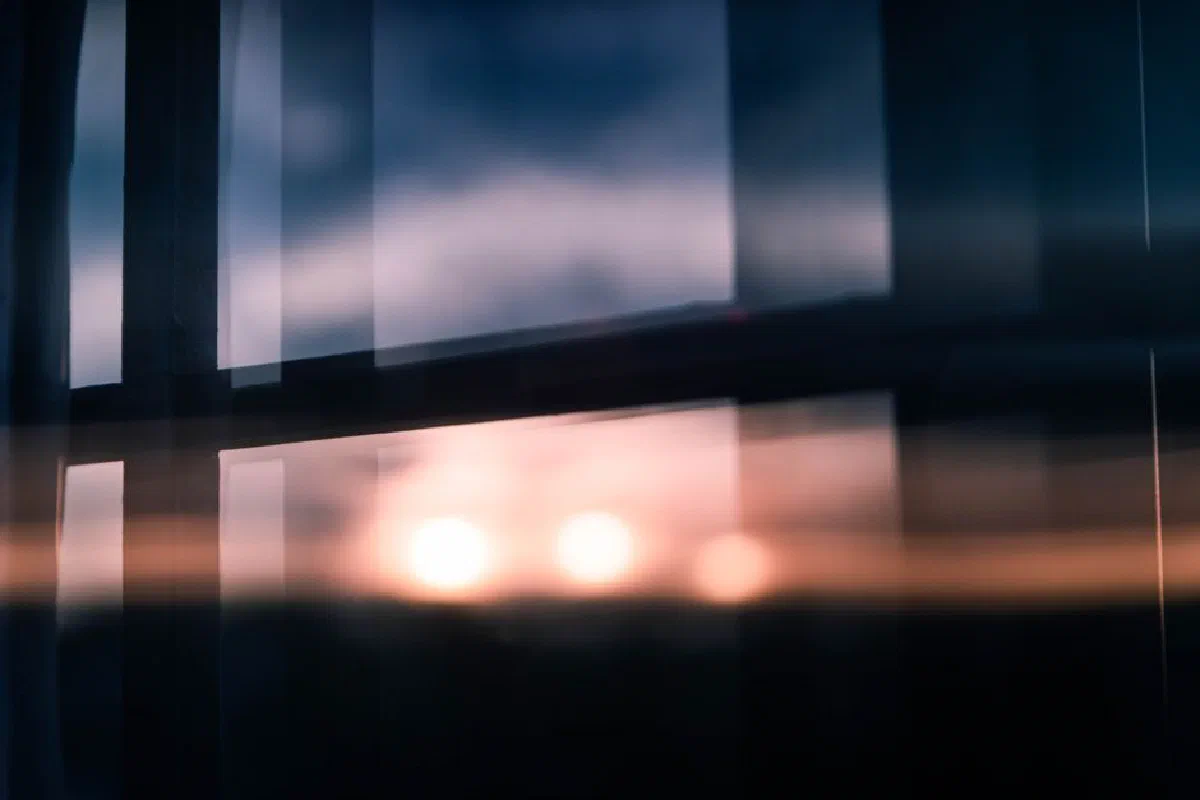Blurry sunset reflection on a window with soft lights and shadows creating a moody atmosphere.