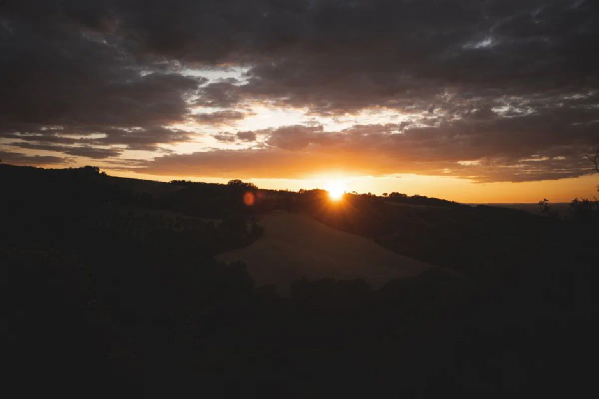 Stunning sunset view highlighting landscape and vibrant sky colors over rolling hills.