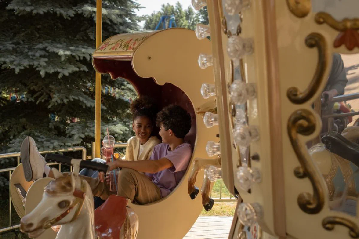 Young couple riding a carousel enjoying a warm summer day at the amusement park.