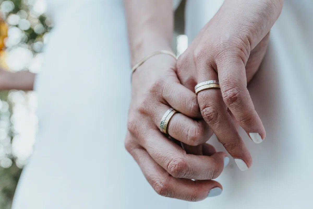 Close-up image of intertwined hands showcasing elegant wedding rings, symbolizing love and commitment.