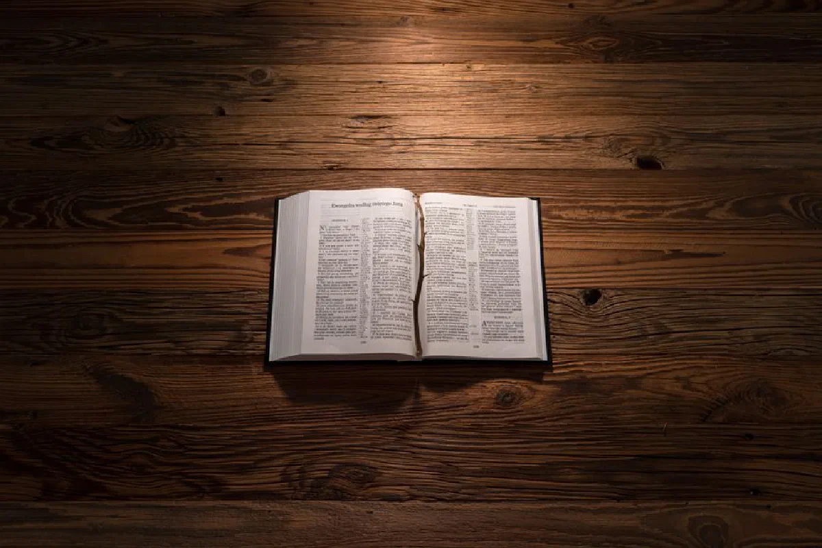 An open Bible on a wooden table, softly lit, symbolizing reflection and spirituality.
