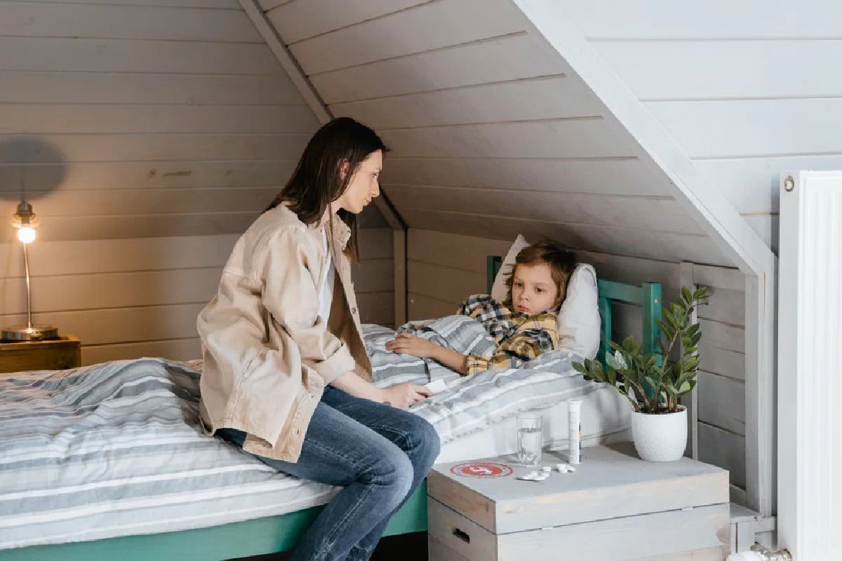 Mother gently caring for her sick child in a cozy bedroom setting, showing love and concern.