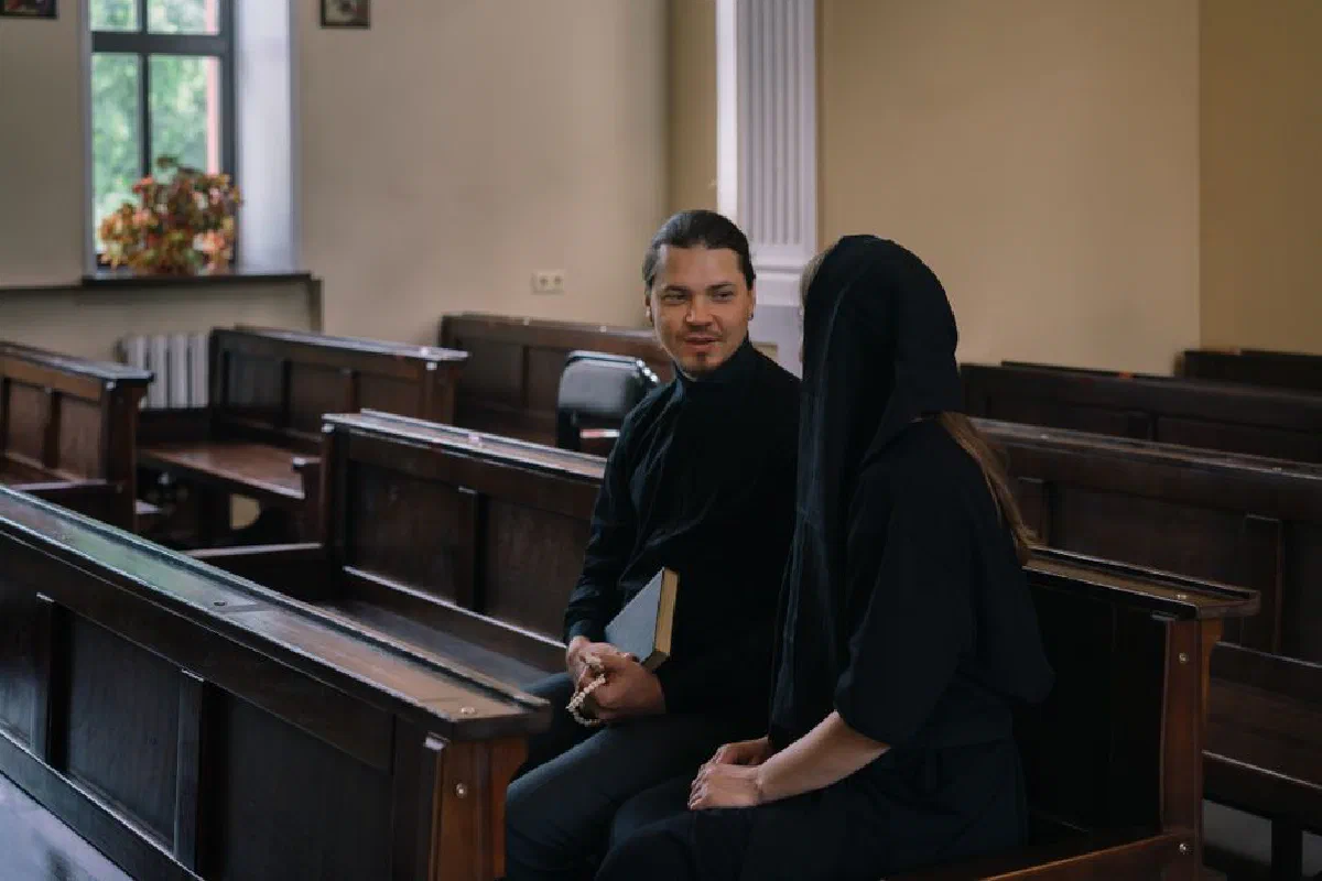 A priest and woman engaged in conversation inside a church, highlighting religious connection.