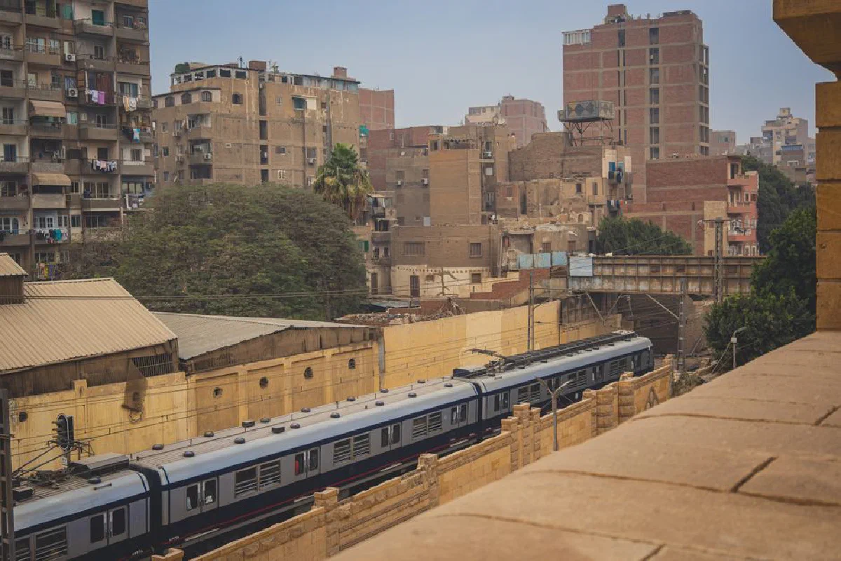 A bustling view of Cairo featuring a train amidst dense urban architecture, showcasing the city's dynamic living environment.