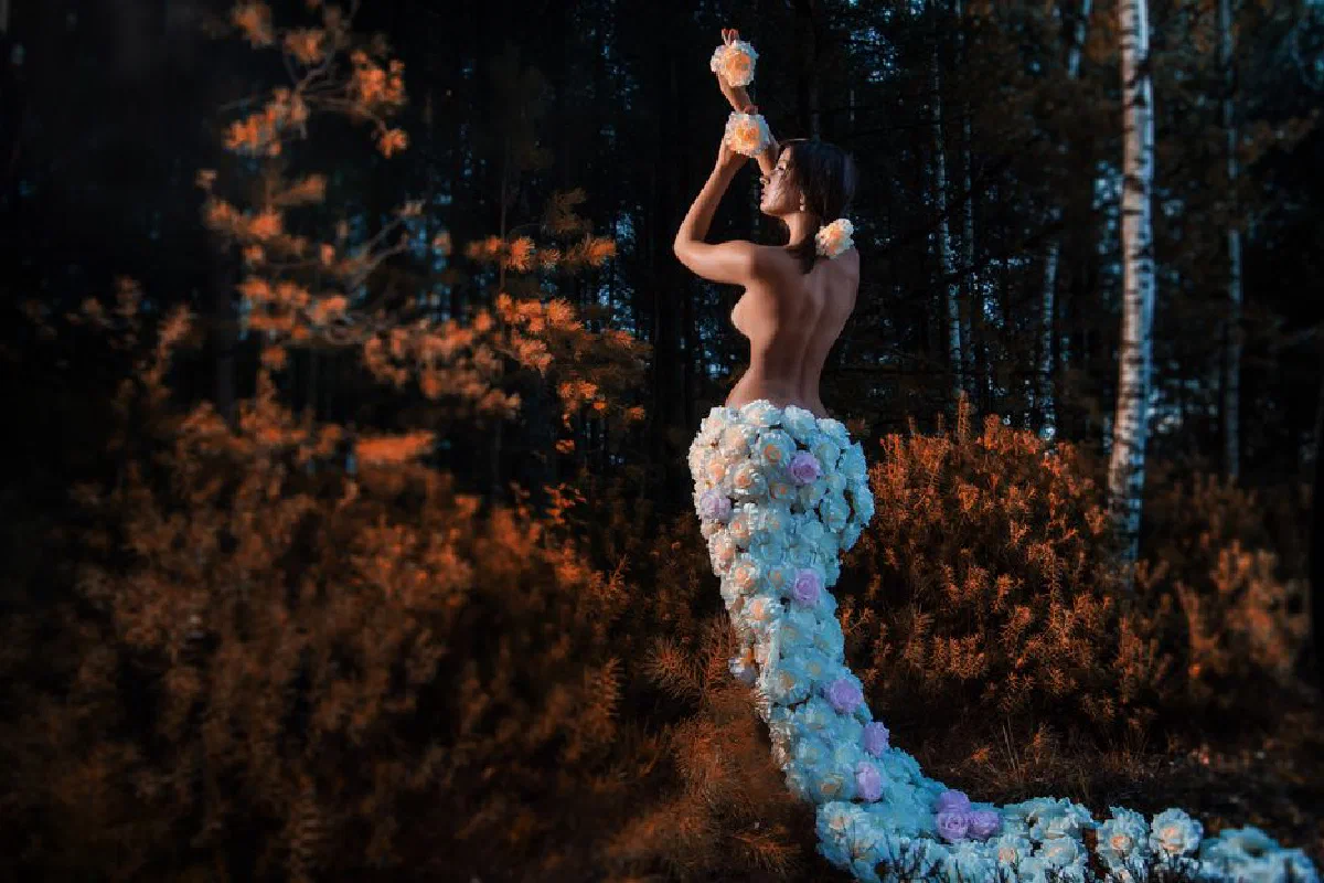 Captivating image of a woman adorned with flowers posing elegantly in an autumn forest.