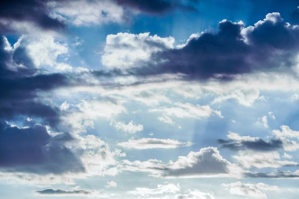 A bright sky filled with dramatic clouds and sunlight streaming through.
