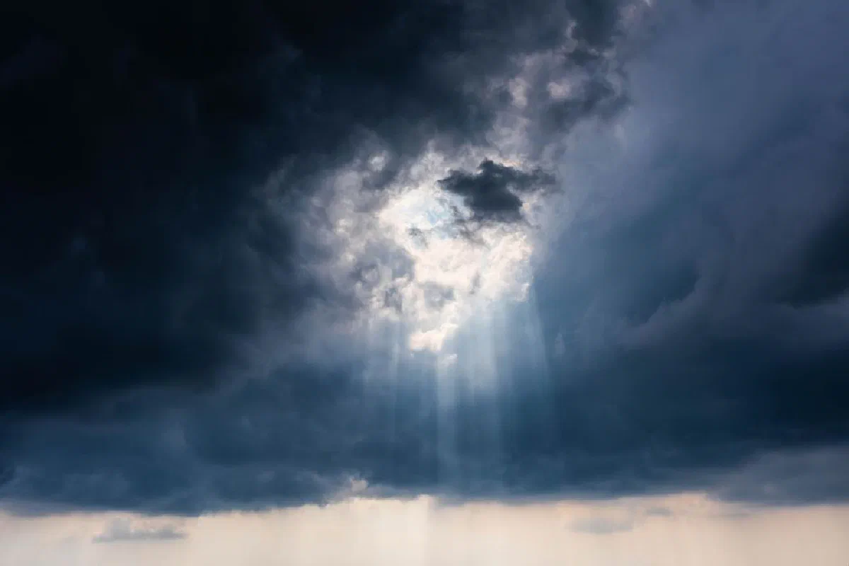 Dramatic sky with sun rays breaking through dark stormy clouds, creating a majestic view.