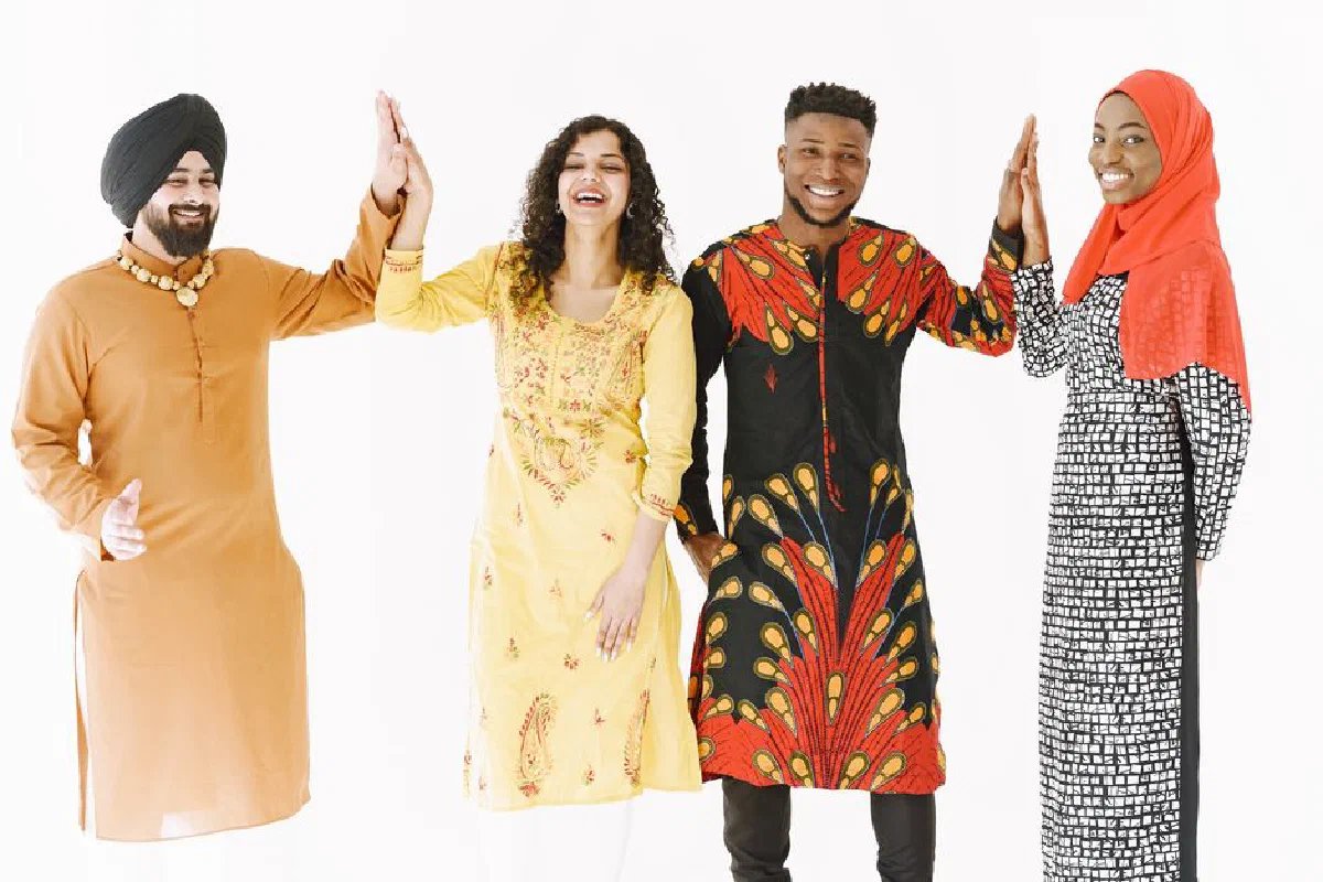 A joyful group of adults from diverse backgrounds high-fiving in traditional clothing.