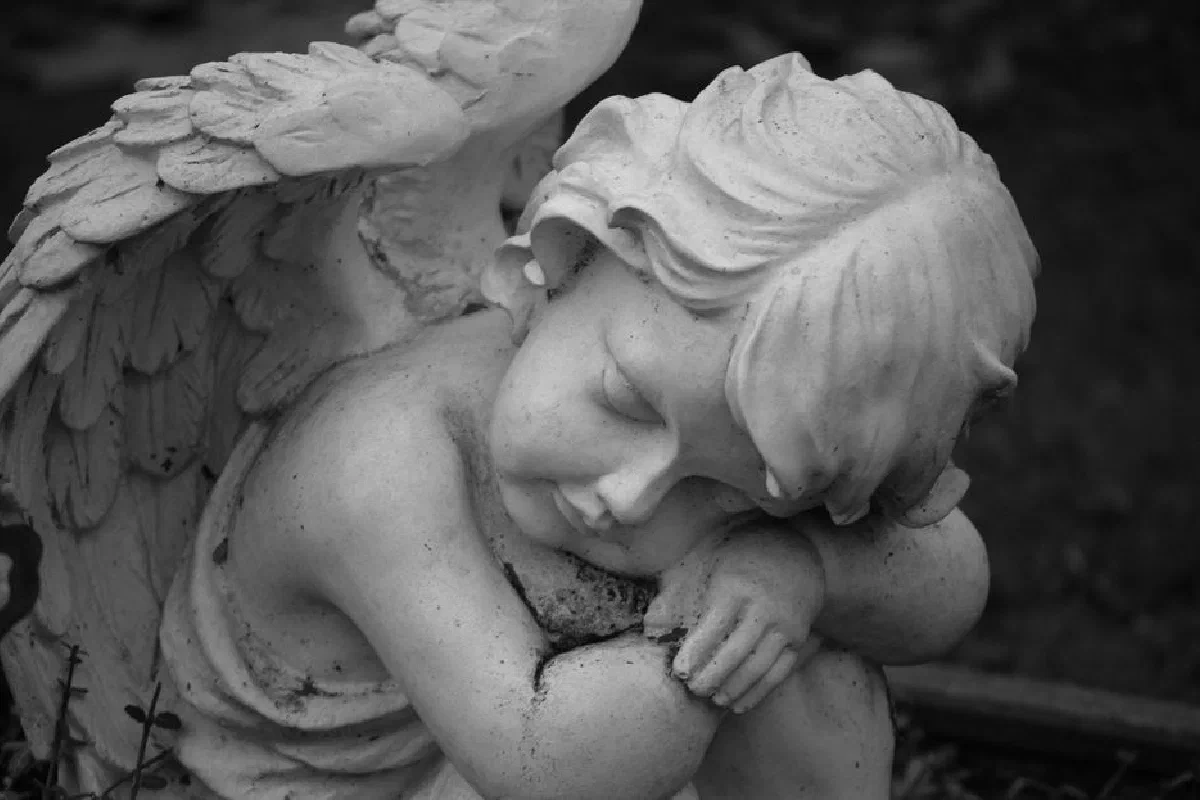 Grayscale image of a resting angel statue in Rhede, Germany.