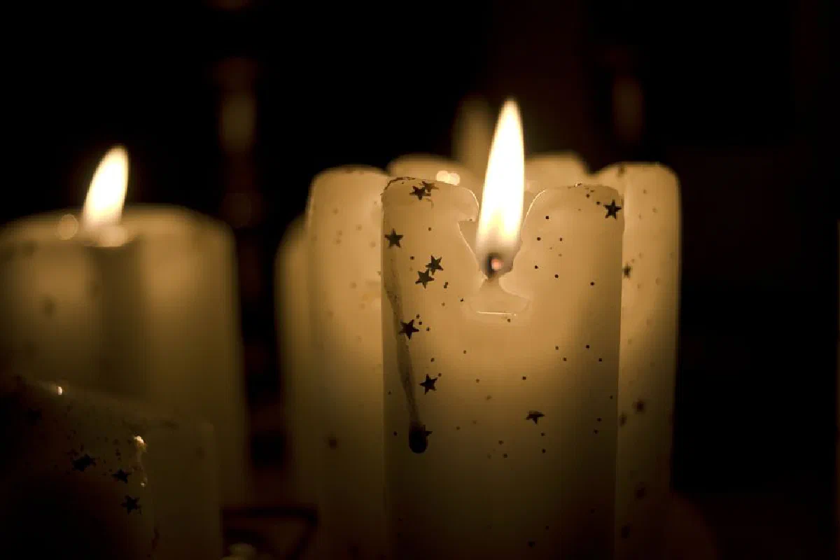 Elegant close-up of burning candles with star patterns casting soft light in darkness.