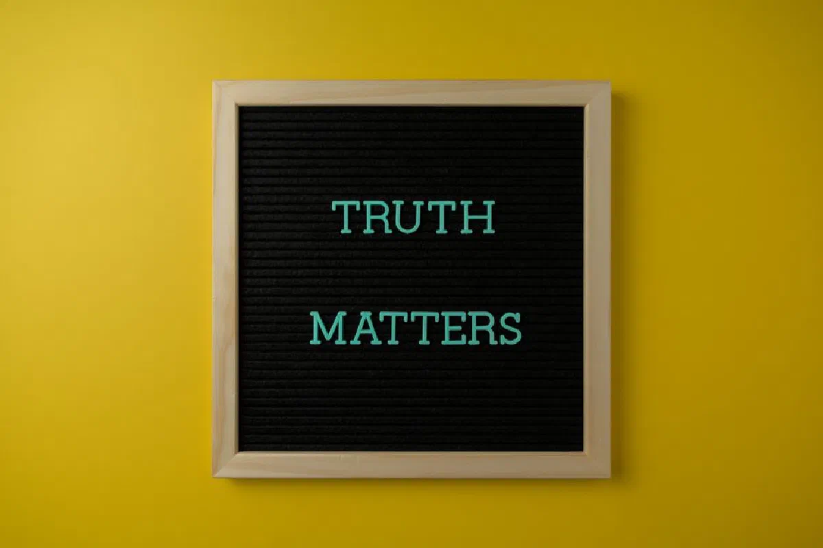 Close-up of black letter board with 'Truth Matters' message on yellow background.