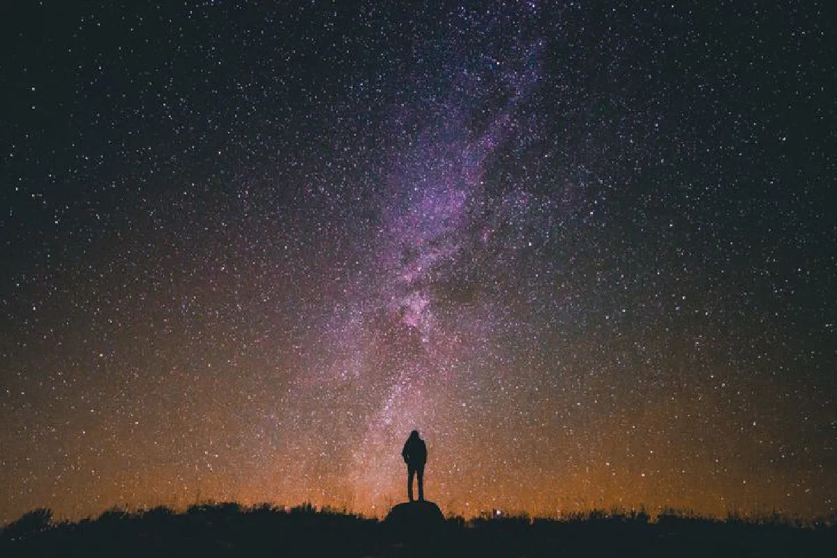 Person silhouetted against a breathtaking night sky filled with stars and the Milky Way galaxy.