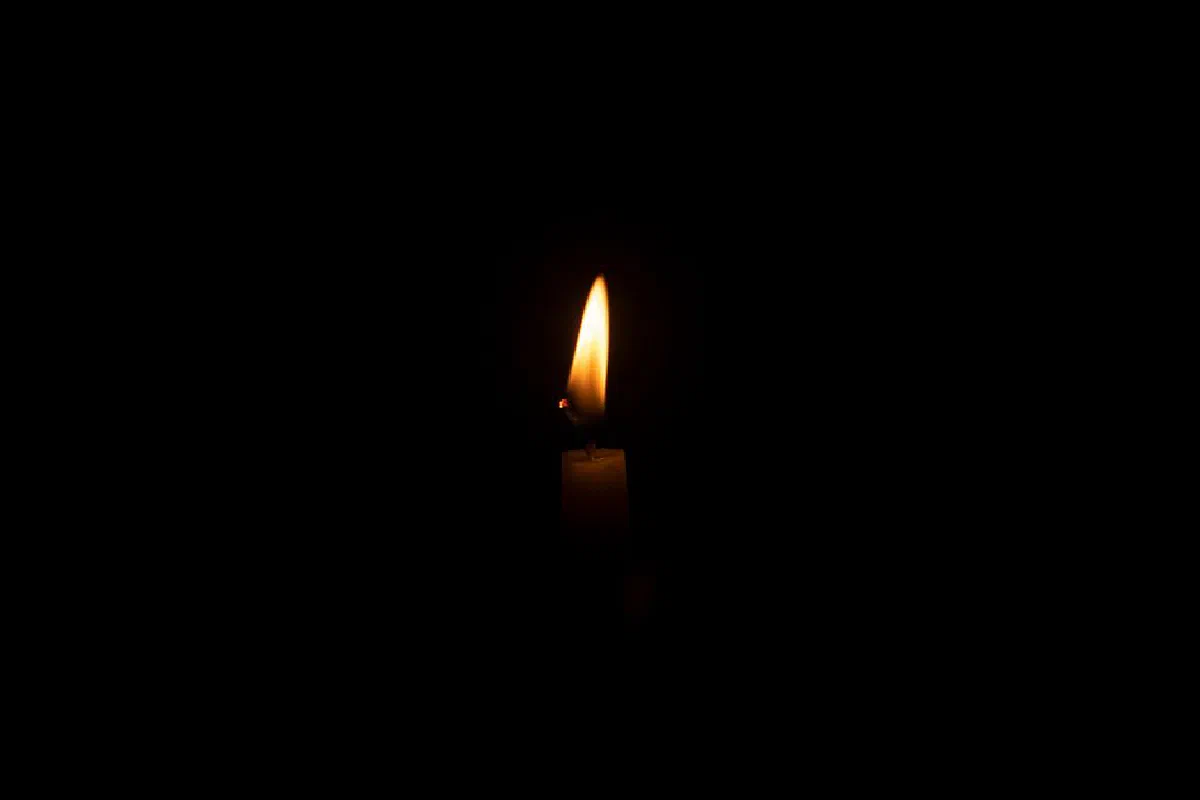 A solitary candle flame illuminates the darkness, creating a warm and tranquil atmosphere.