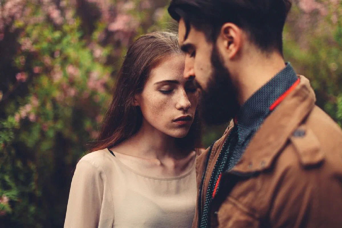 A romantic closeup of a young couple in an outdoor setting, expressing intimacy.