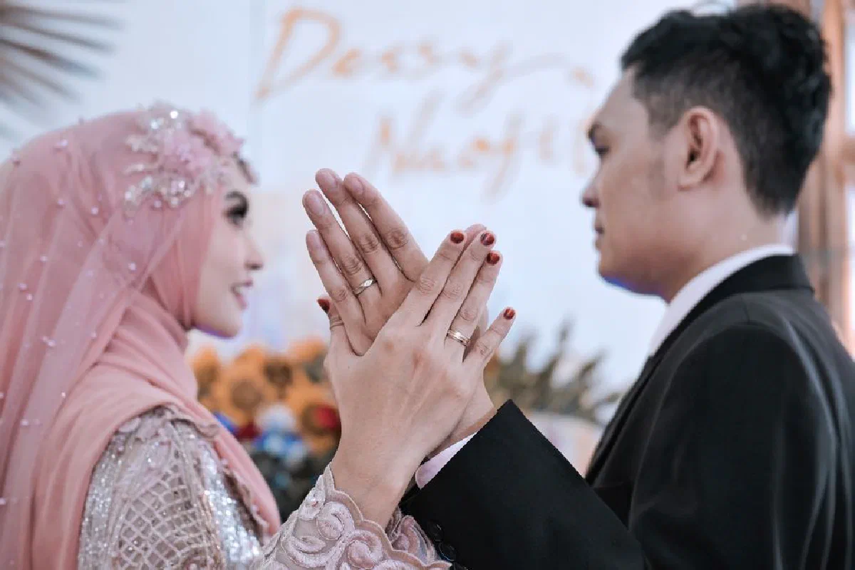 Happy couple exchanging rings during a joyful wedding ceremony with cultural attire and traditional decorations.