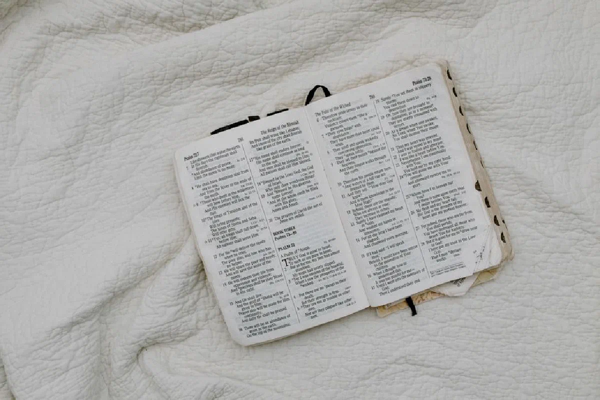 An overhead shot of an open Bible resting on a soft quilt, evoking a peaceful and contemplative atmosphere.
