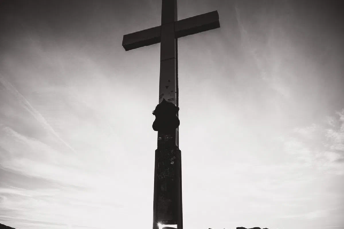 Black and white silhouette of a cross on Zugspitze summit during sunrise, Bavaria, Germany.