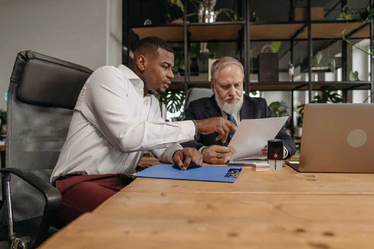 Two businessmen reviewing documents together in a modern office environment.