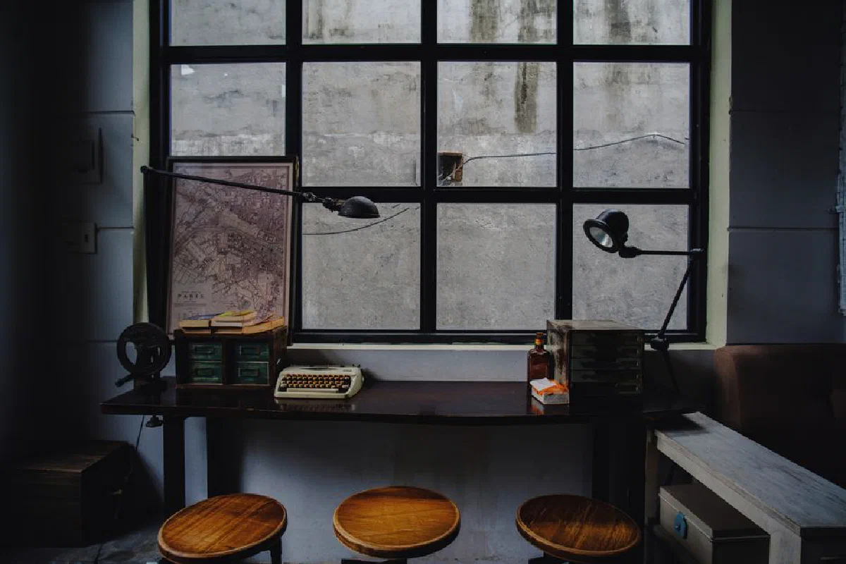 A nostalgic workspace featuring a typewriter, map, and industrial window setting.
