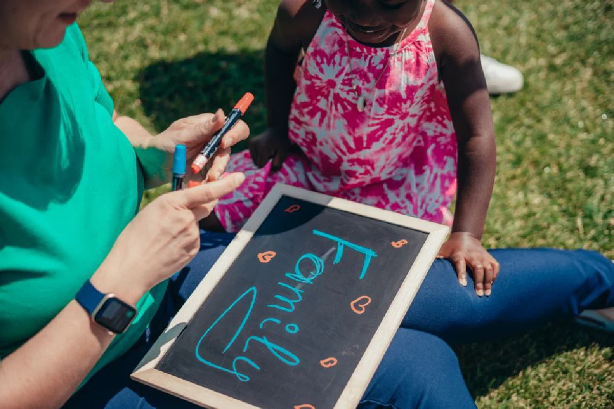 Mother and child bonding outdoors with a chalkboard, emphasizing family values.
