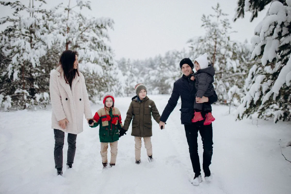 Family enjoying a snowy winter day in the forest, walking and bonding together, capturing joyful moments.