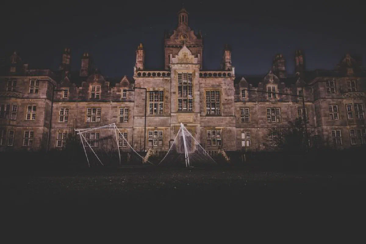 A nighttime photograph of an eerie, abandoned mansion in Wales, exuding a spooky atmosphere.