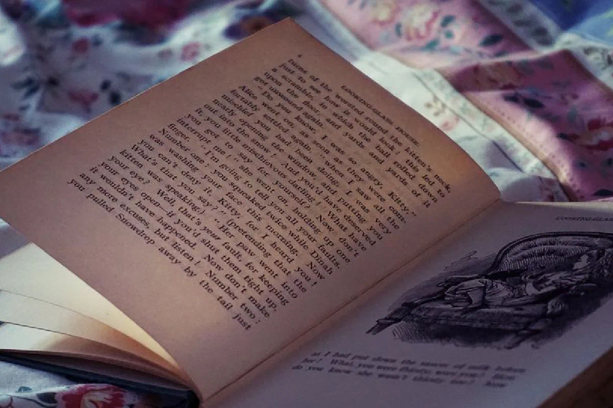 An open vintage book resting on a floral bedspread, evoking a cozy and nostalgic atmosphere.