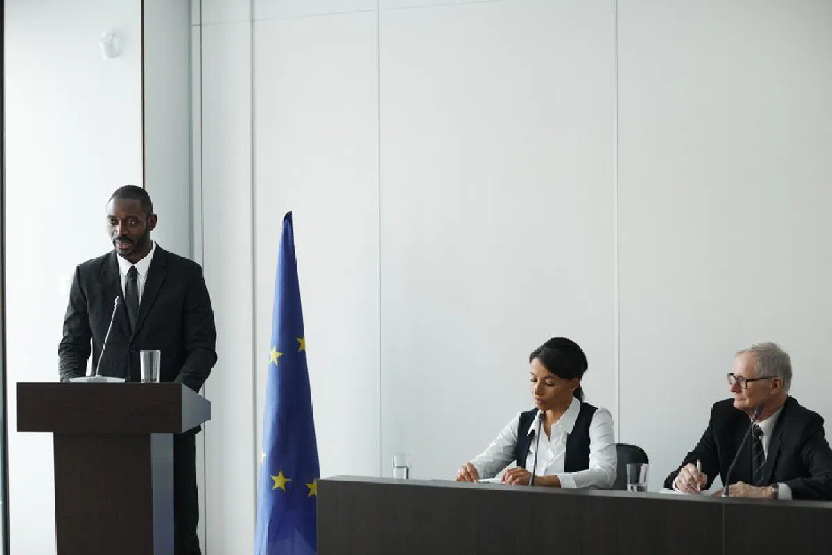 Professional business conference with EU flag, diverse speakers in suits discussing diplomacy.