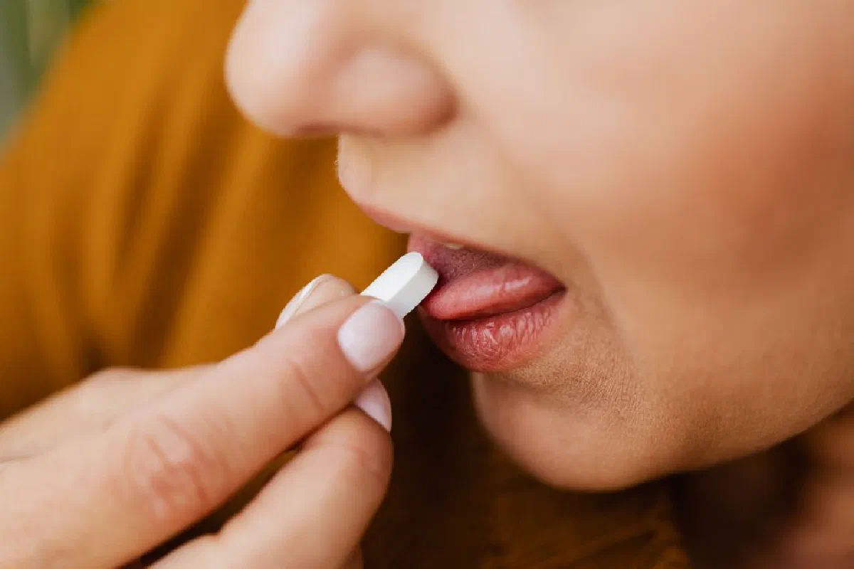 Close-up image of a woman taking a pill, emphasizing health and medication.