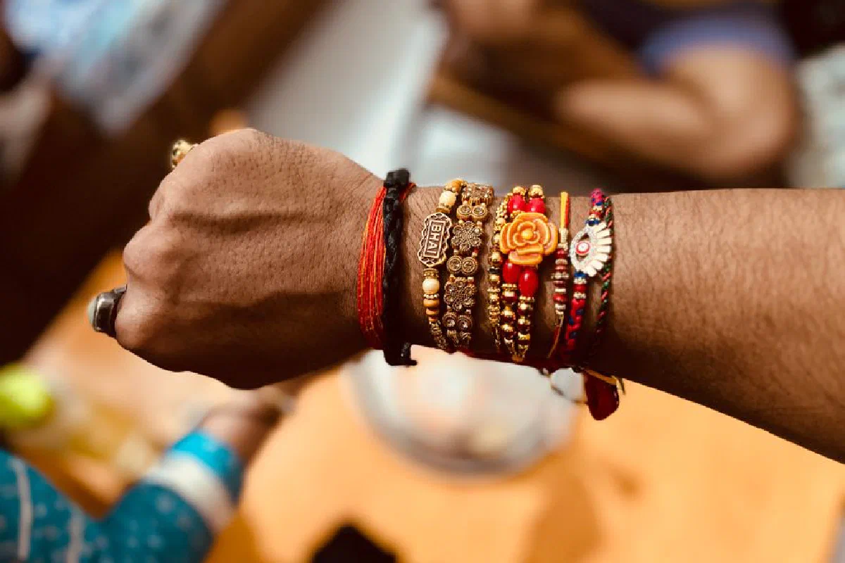 Close-up of a male wrist adorned with traditional Rakhi bracelets symbolizing love during Indian festivals.