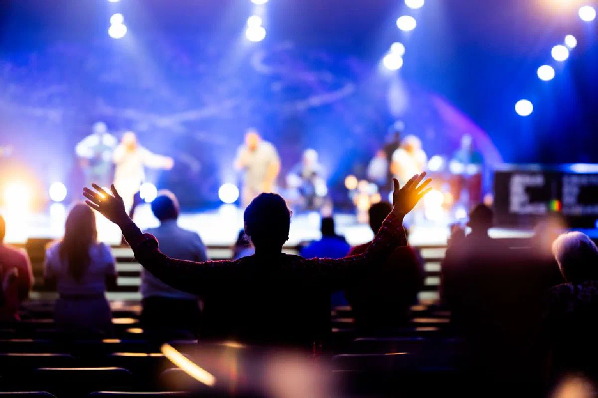 A vibrant worship gathering with enthusiastic attendees and a lively stage performance.