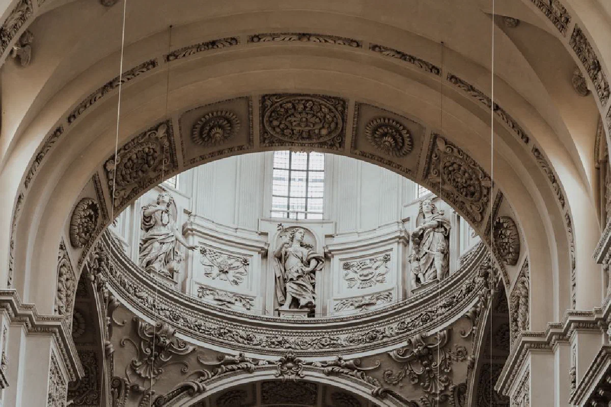 A detailed view of ornate Baroque arches and sculptures in a cathedral ceiling, showcasing classic European architecture.