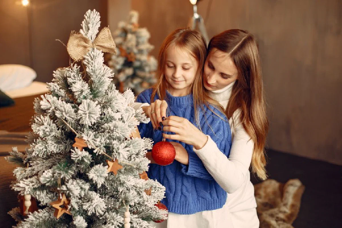 A warm family moment with mother and daughter decorating a Christmas tree together.