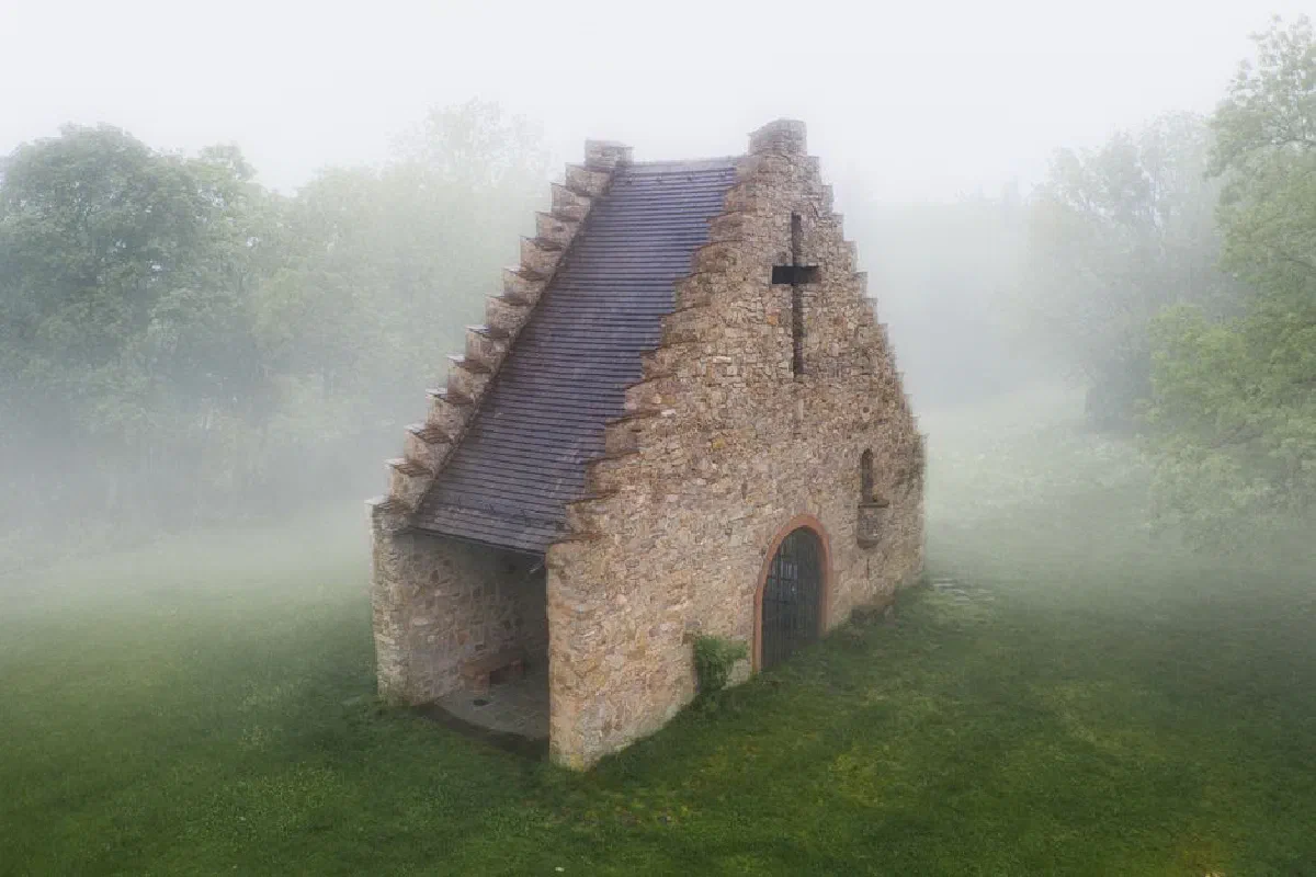 A solitary stone chapel in a foggy landscape, creating a mysterious atmosphere.
