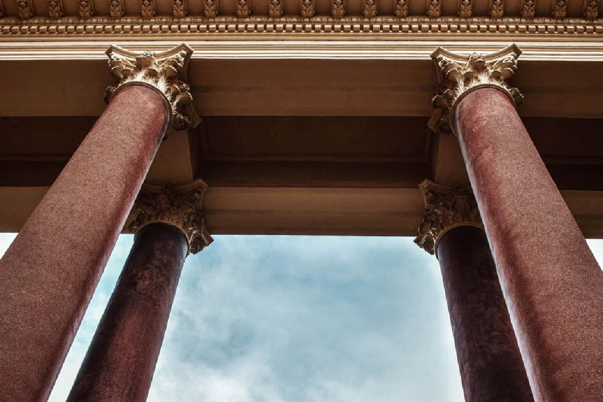 Low-angle view of ornate columns against a blue sky, showcasing architectural elegance.
