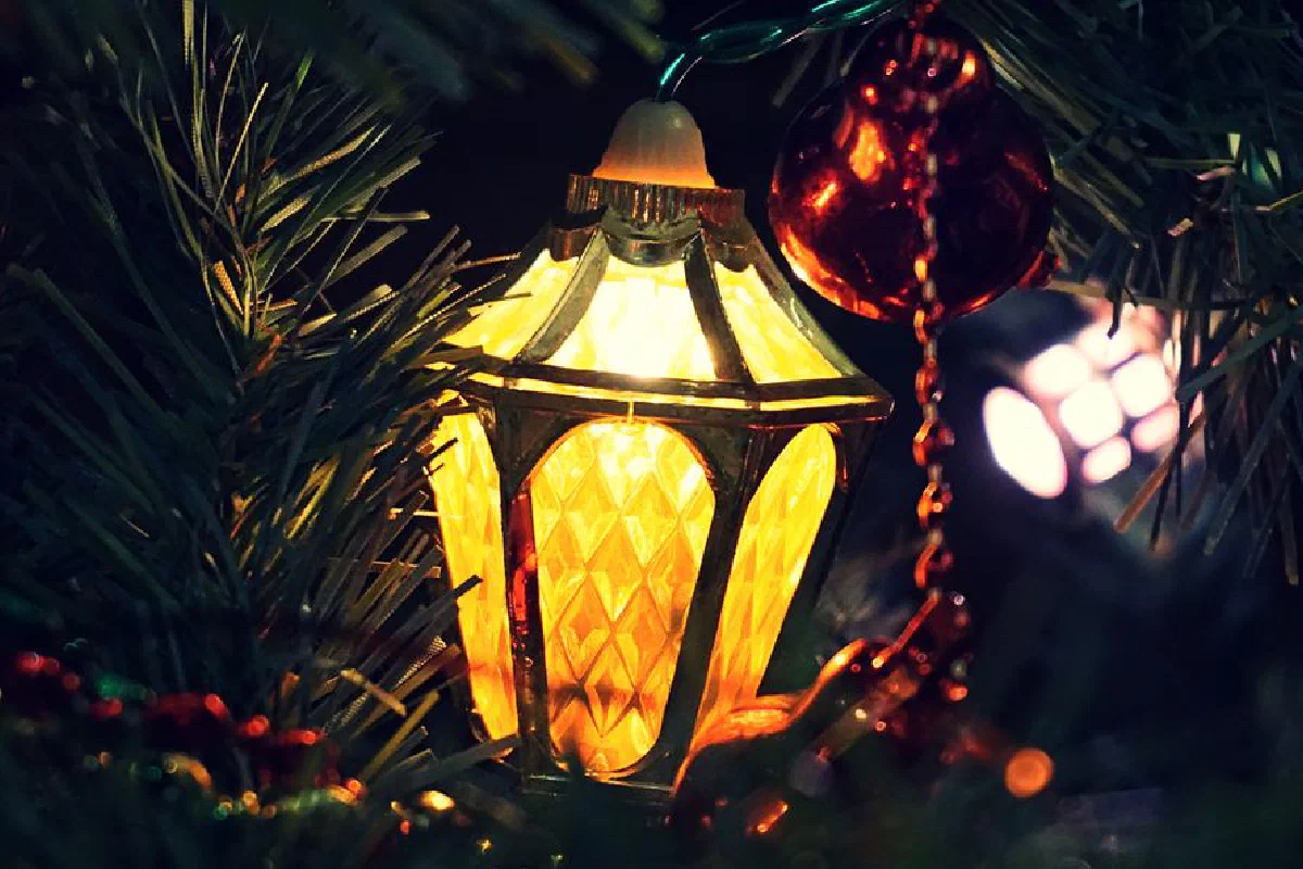 Close-up of an illuminated lantern ornament on a Christmas tree with decorations.