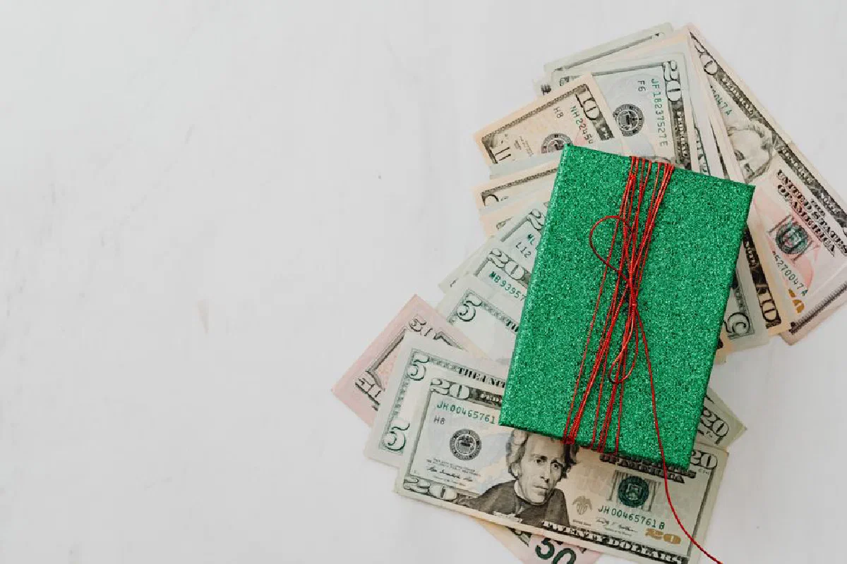 Green gift box on a pile of dollar banknotes showcasing a concept of monetary value and gift-giving.