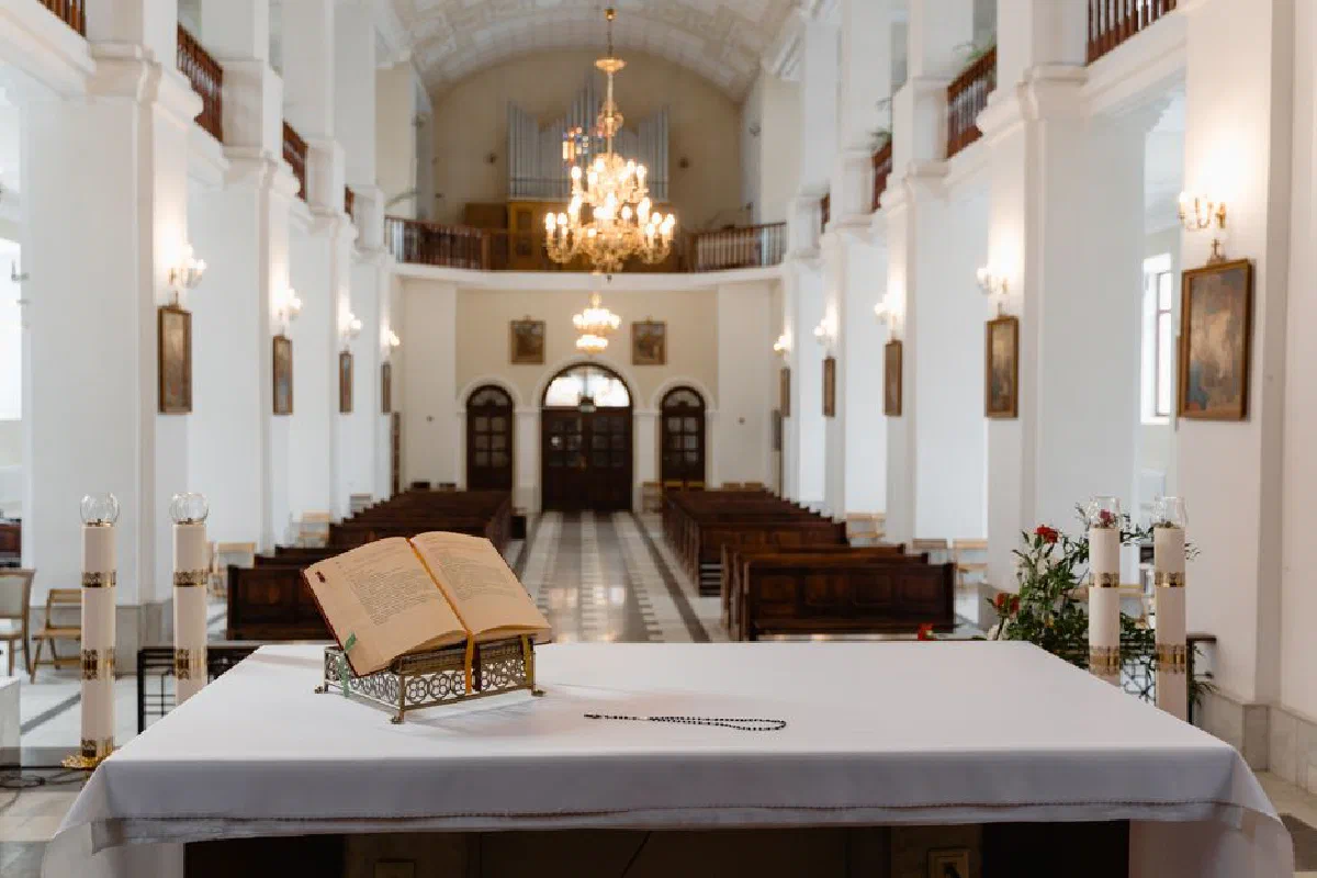 A beautifully lit church interior with an open Bible on the altar and empty pews, exuding a serene atmosphere.