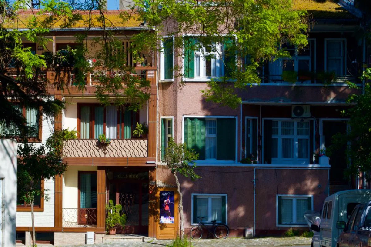Colorful apartment facade with lush greenery and sunlight in an urban setting.