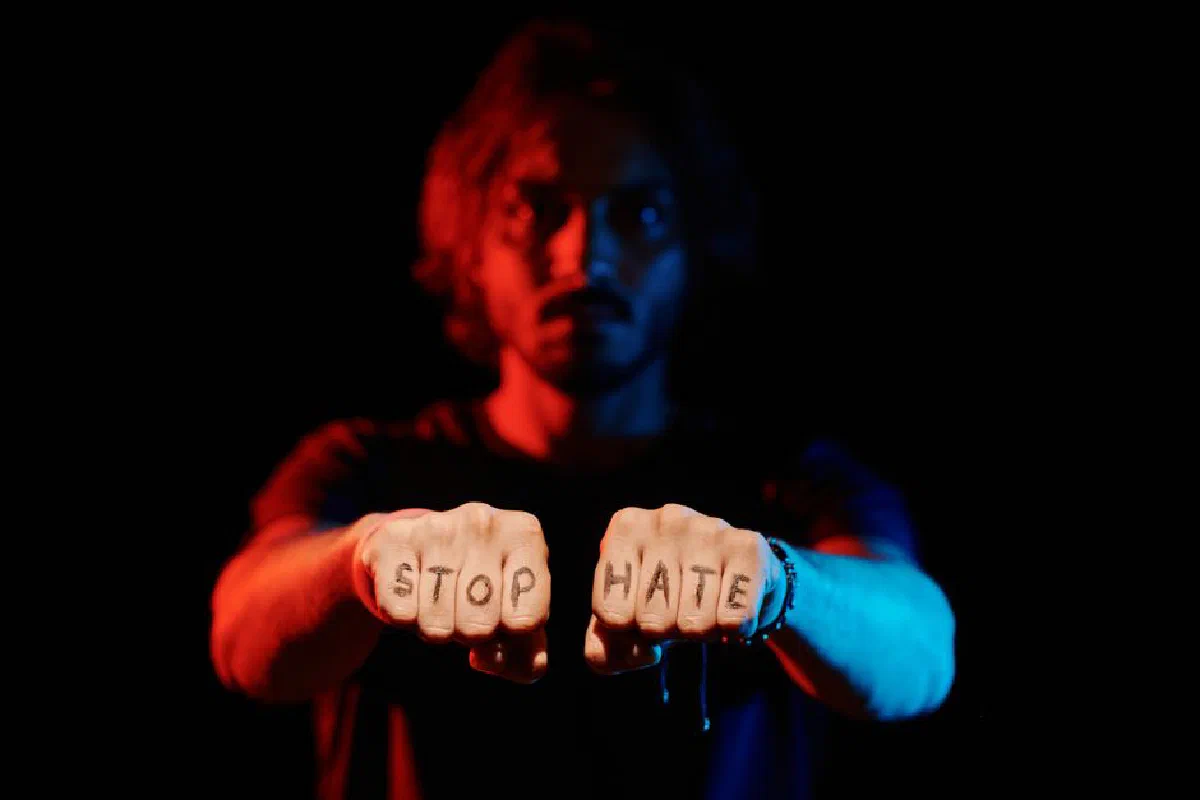 A dramatic portrayal of an anti-hate message spelled out on hands against a dark background.