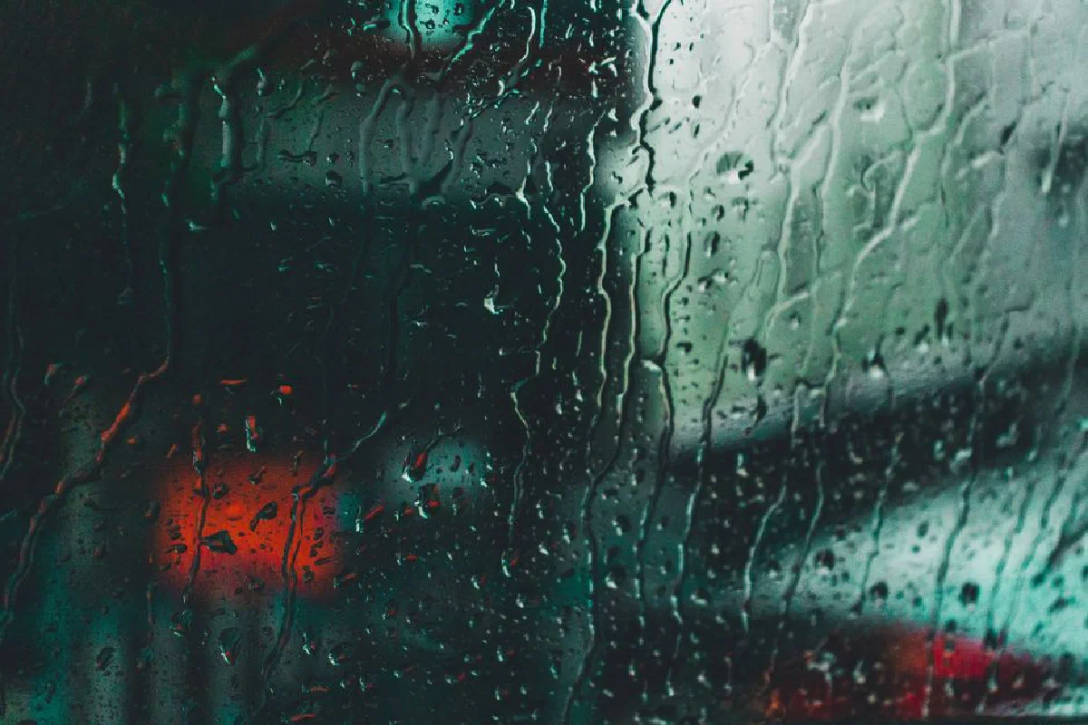 Artistic capture of rain on a window with blurred city lights in Kolkata, India.