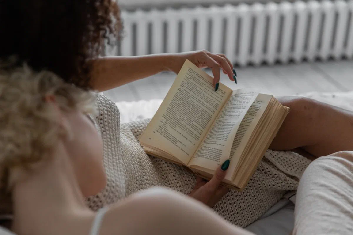 A person reading a book indoors, enjoying a relaxing and cozy environment.