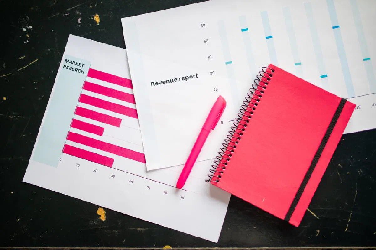 Overhead shot of a desk with charts, a red notebook, and a pen for business analysis.