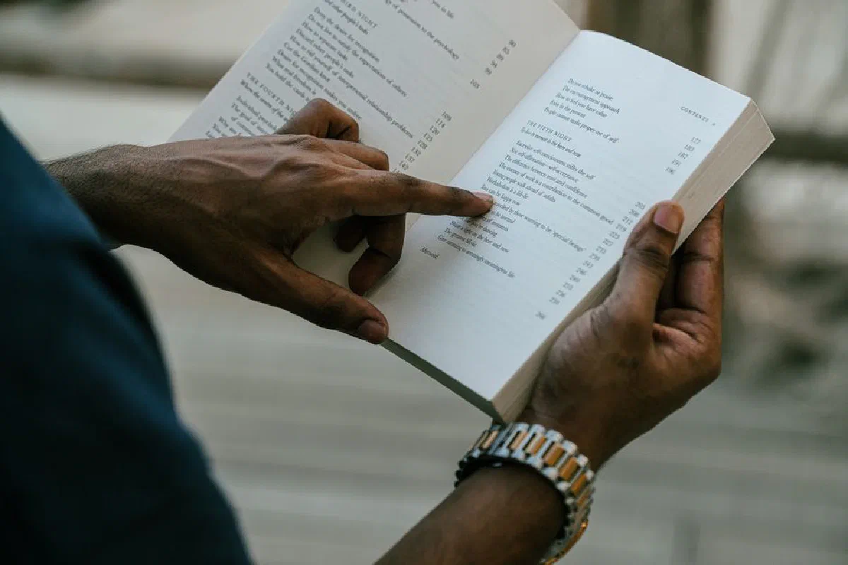 Close-up of a person reading an open book outdoors, capturing focus and inspiration.