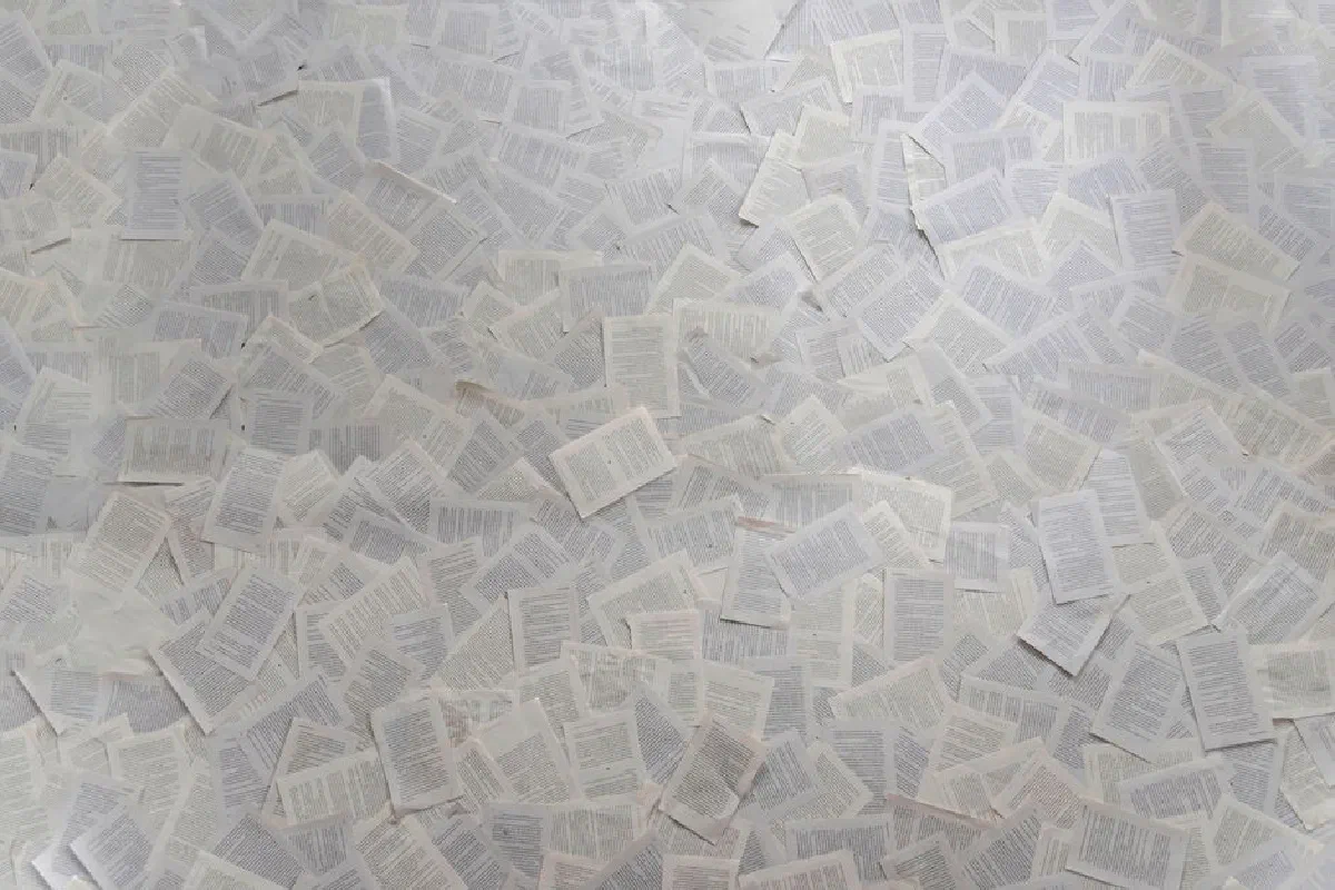 Abstract composition of numerous loose book pages overlapping indoors.