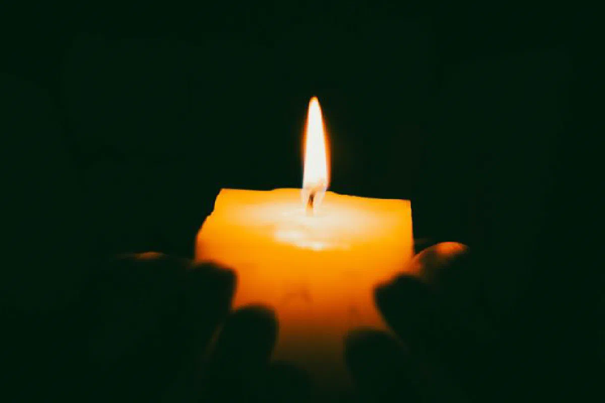 A close-up of hands holding a candle, providing soft illumination in darkness.