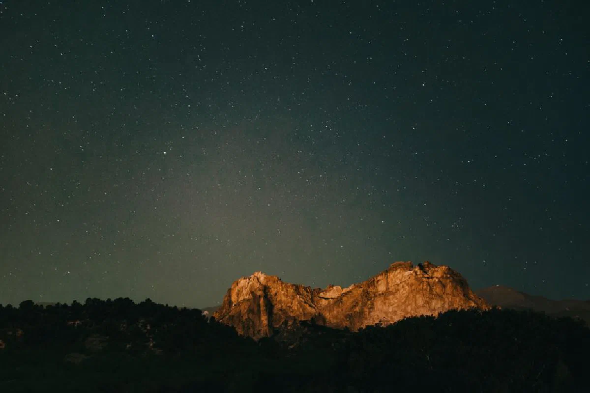 A serene night view of a mountain under a starry sky in Colorado Springs.