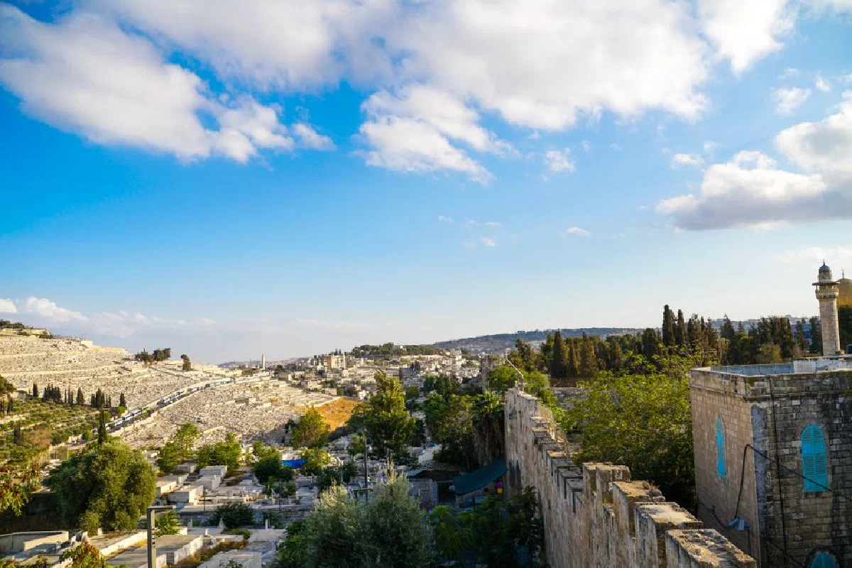 Explore the historic landscape of Jerusalem under a clear blue sky with lush greenery and ancient architecture.
